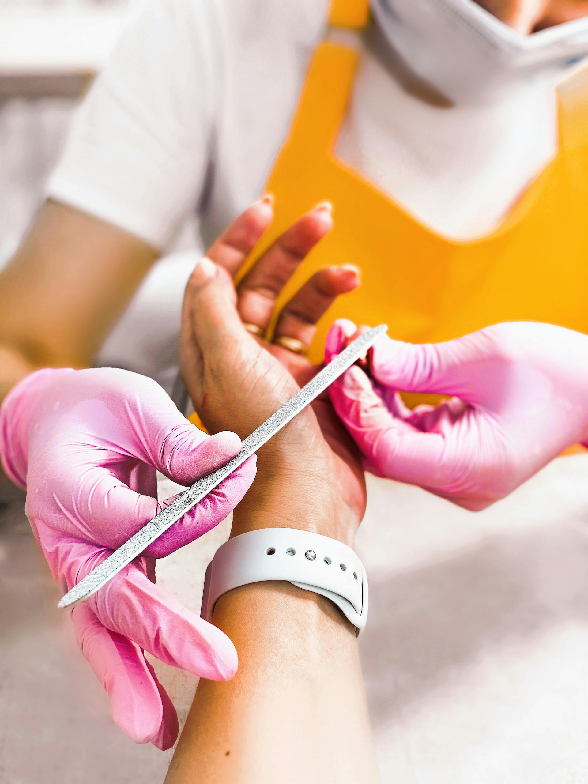 Close-up of a nail technician filing a client's nails with precision and care.
